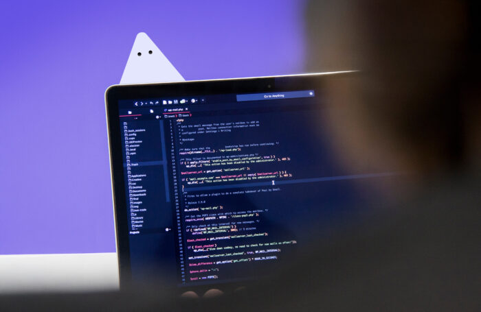Image d'un écran d'ordinateur portable ouvert sur un IDE, une petite silhouette de nacho est visible derrière le coin supérieur gauche de l'écran.